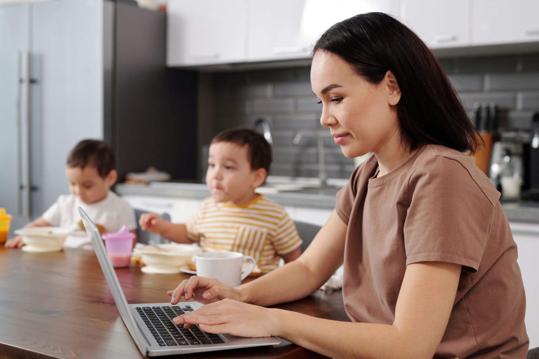 A mother opening a dinner recipe while her children eat nearby